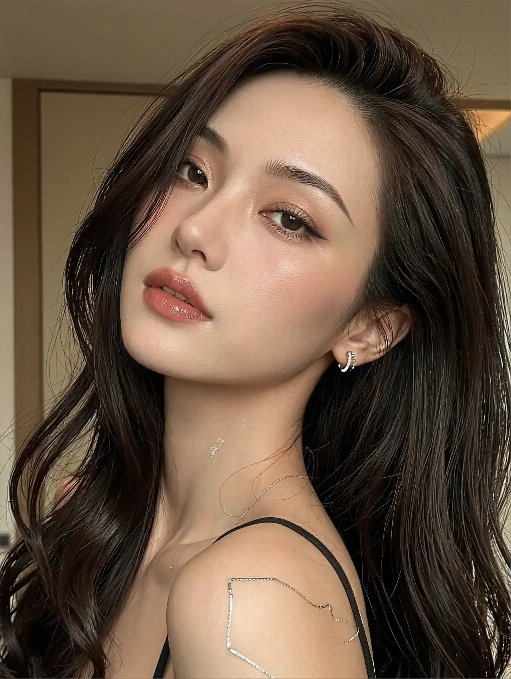 Close-up portrait of a woman with glossy lips and a small hoop earring in warm peach tones